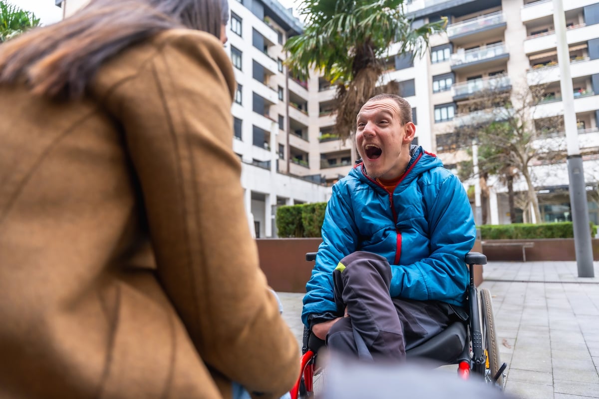 A young man with Down syndrome smiling with a caregiver